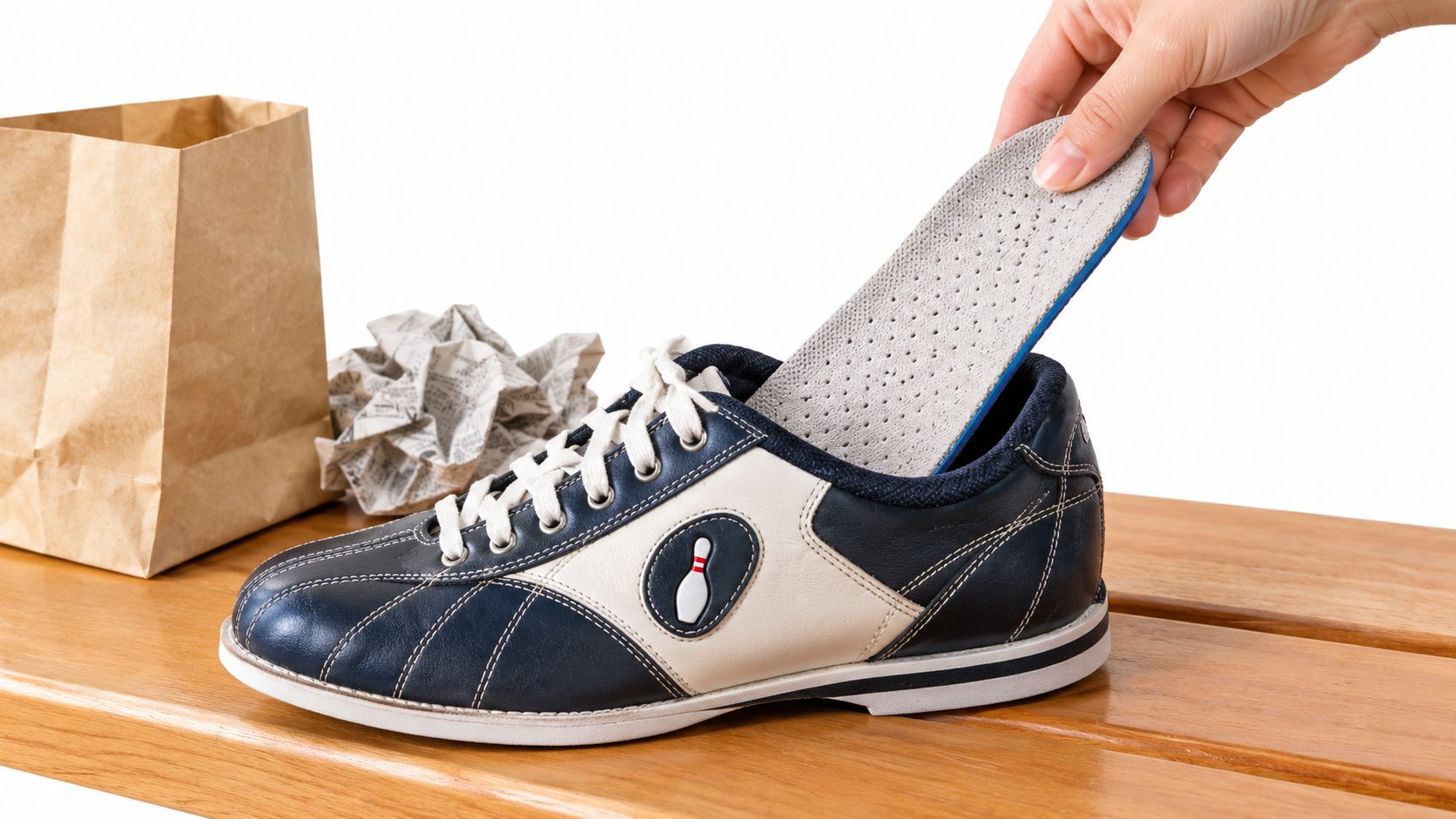 A hand placing a cushioned shoe insole into a blue and white professional bowling shoe.