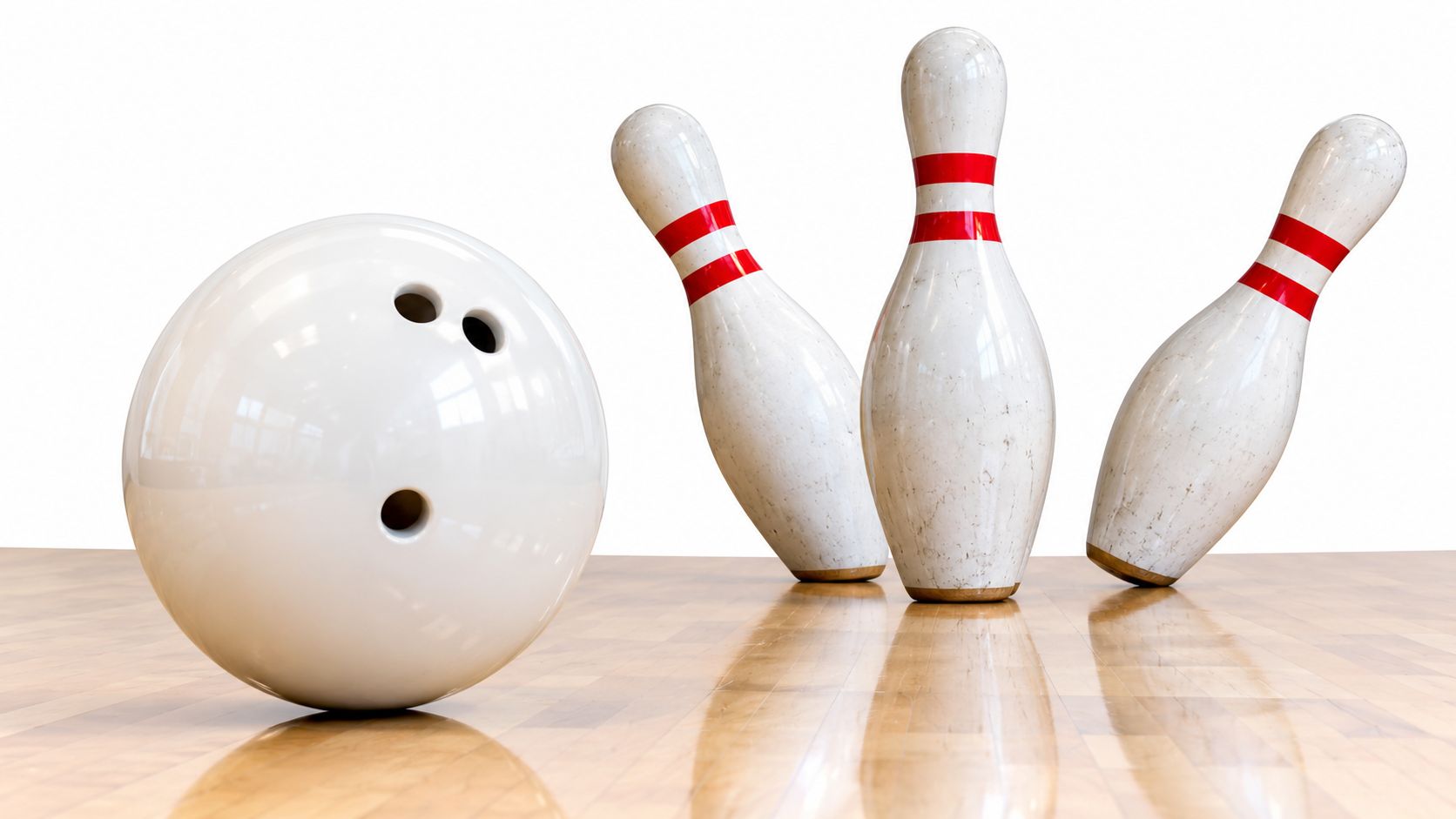 A glossy white bowling ball positioned on a wooden floor near three bowling pins being struck